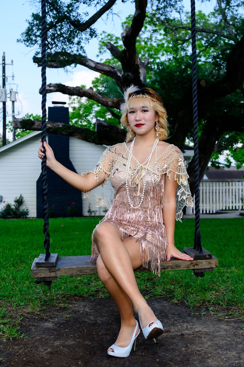 A glamorous 1920s style swing scene with a beaded flapper dress and white heels on a wooden garden seat.
