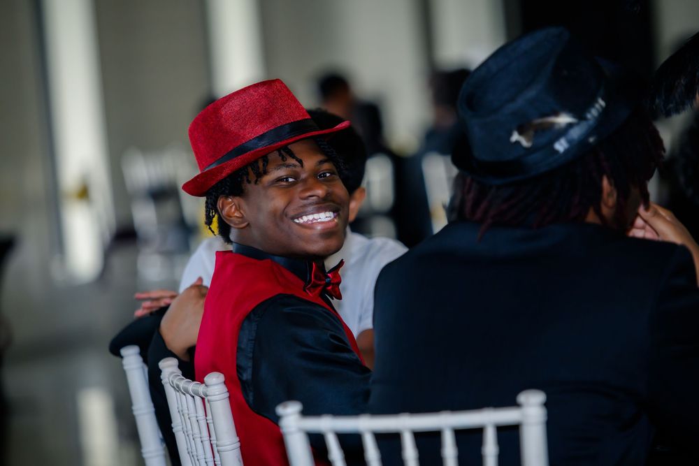 A person wearing a bright red hat and scarf looks back over their shoulder with a cheerful smile.