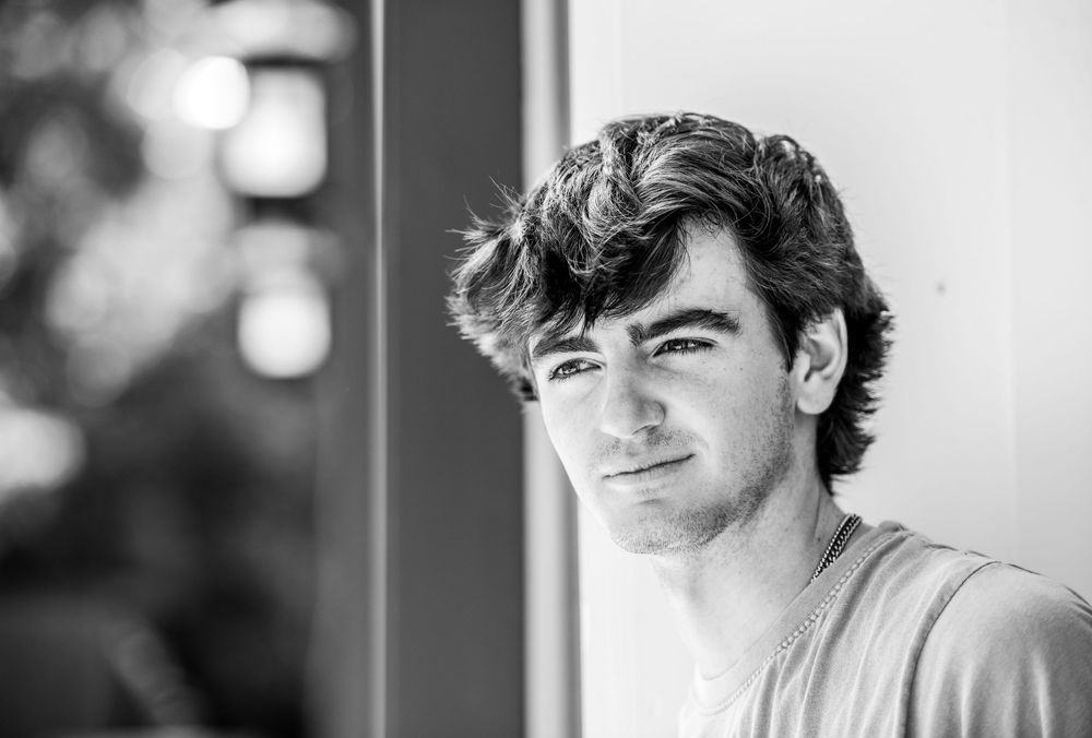 Black and white portrait of person with tousled hair in casual attire.