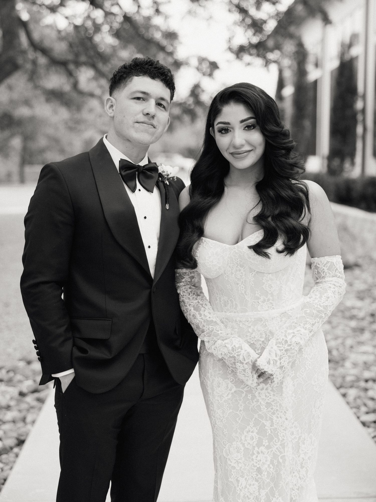 A bride and groom walking together and laughing during their black and white wedding photoshoot.