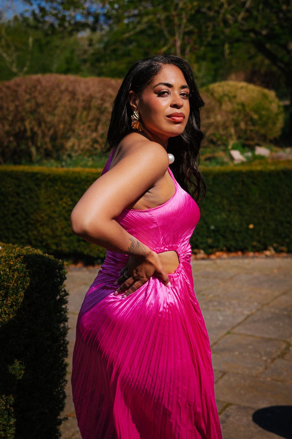 personal branding in the Christchurch mansion garden ,Ipswich.bold colours, cultural fusion, woman in pink dress, looking back, in her power