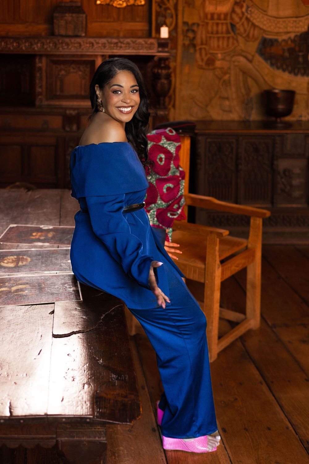 personal branding  at Tudor room in the Christchurch mansion ,Ipswich.bold colours, cultural fusion,woman leaning on desk, smiling,confident