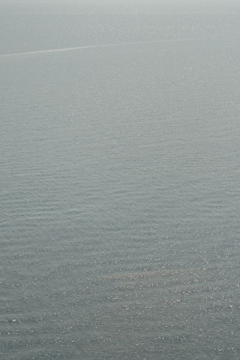 Tranquil grey seascape showing rippling water surface extending to misty horizon.
