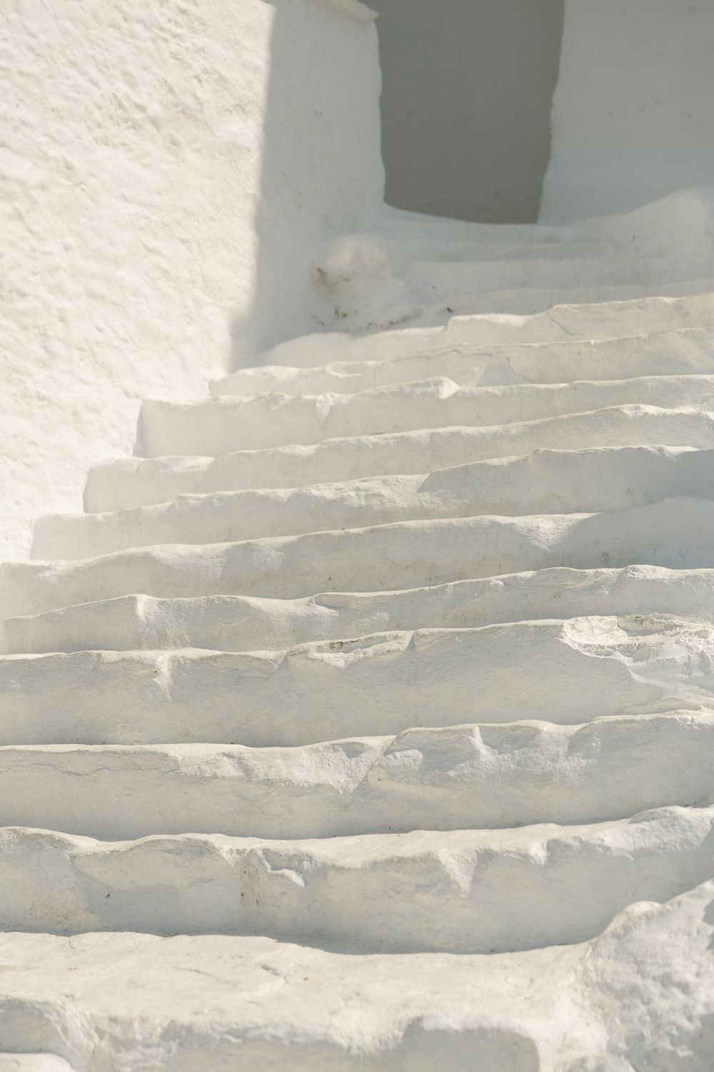 White painted stone steps with sunlight and shadows creating geometric patterns.