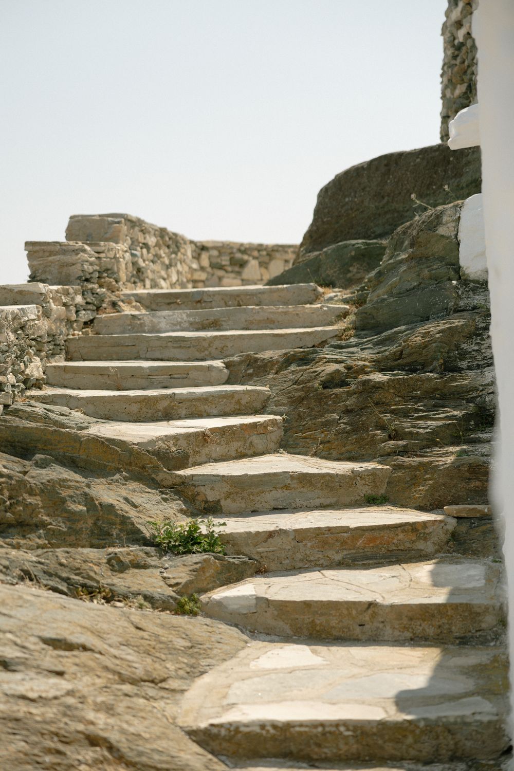 Weathered stone steps wind upward through rustic Mediterranean architecture. Wedding photographer Sifnos
