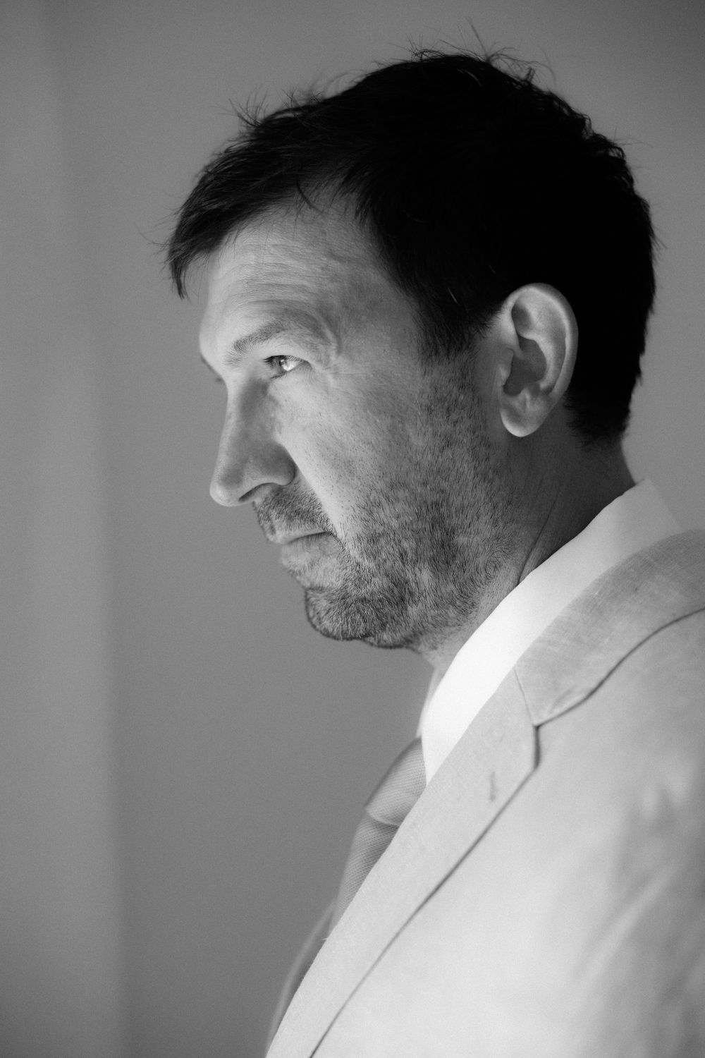 Black and white profile portrait of a person in a light colored jacket. Wedding photographer Sifnos