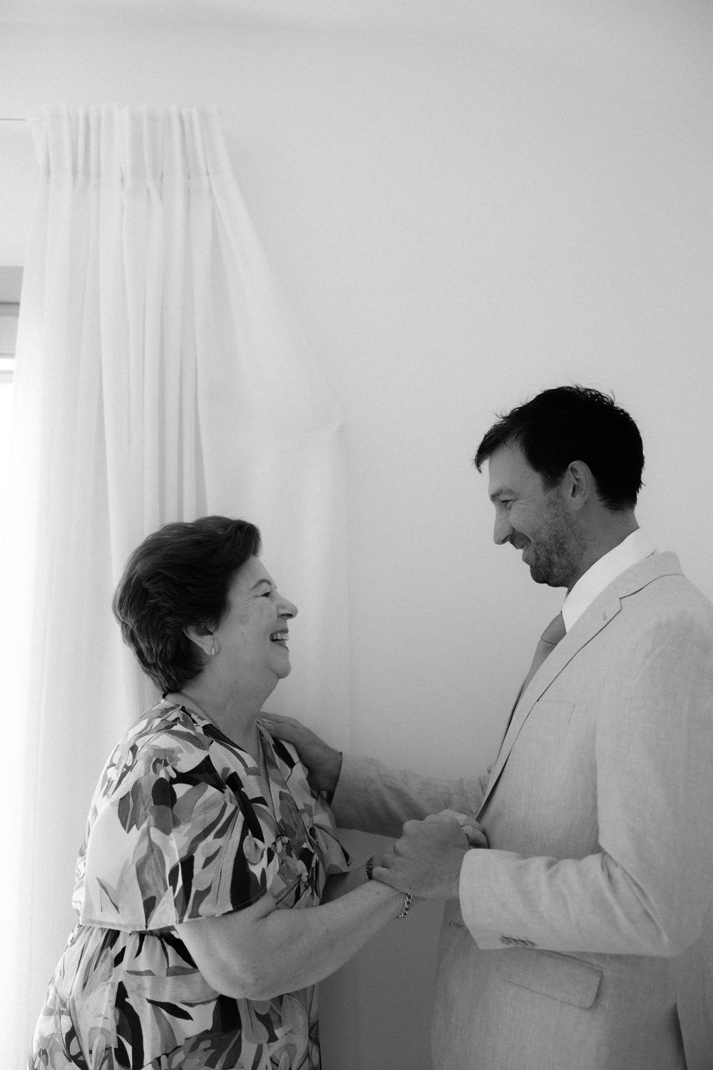 A touching moment shared between two people in a bright white room. Wedding photographer Sifnos