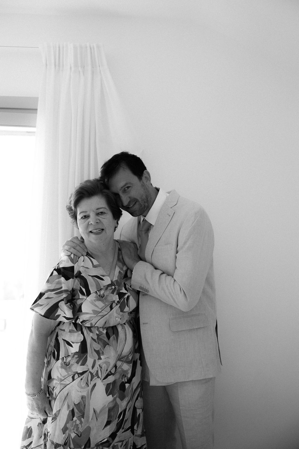 Two people share an intimate moment against white interior wall.