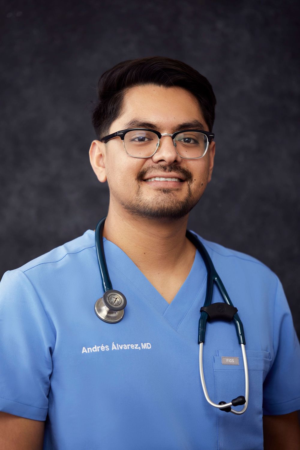 Medical professional in light blue scrubs and stethoscope poses for headshot.