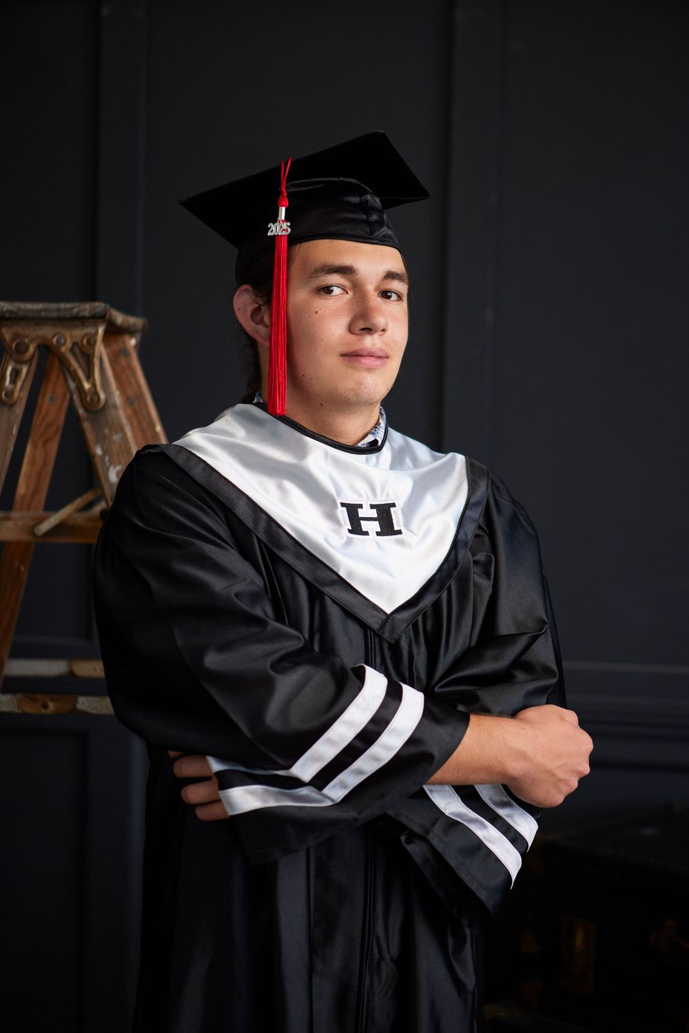 Graduate in black academic regalia poses against dark background in multiple artistic angles.