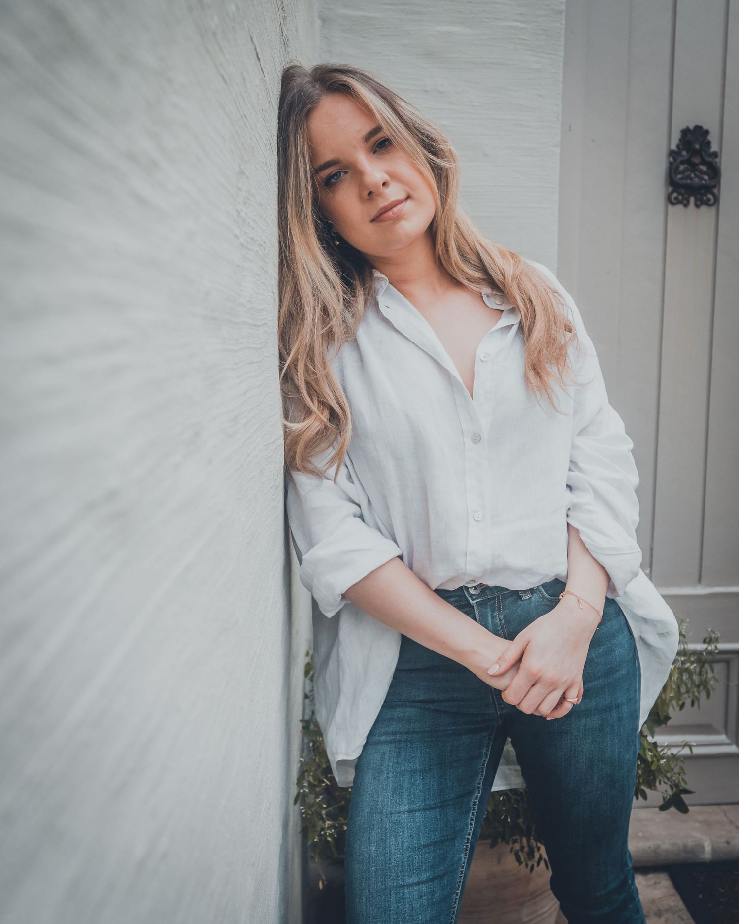 Fashion portrait series showing casual style with white button-down shirt and blue jeans in natural lighting.