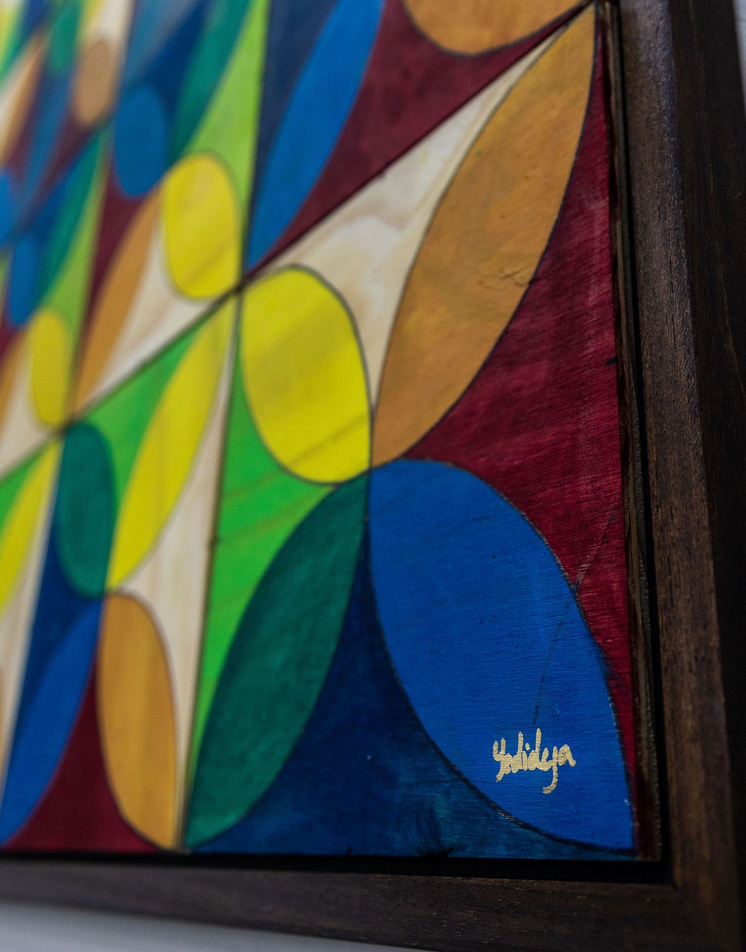 Close-up detail of a colorful abstract painting featuring curved shapes in blue, yellow and green tones.