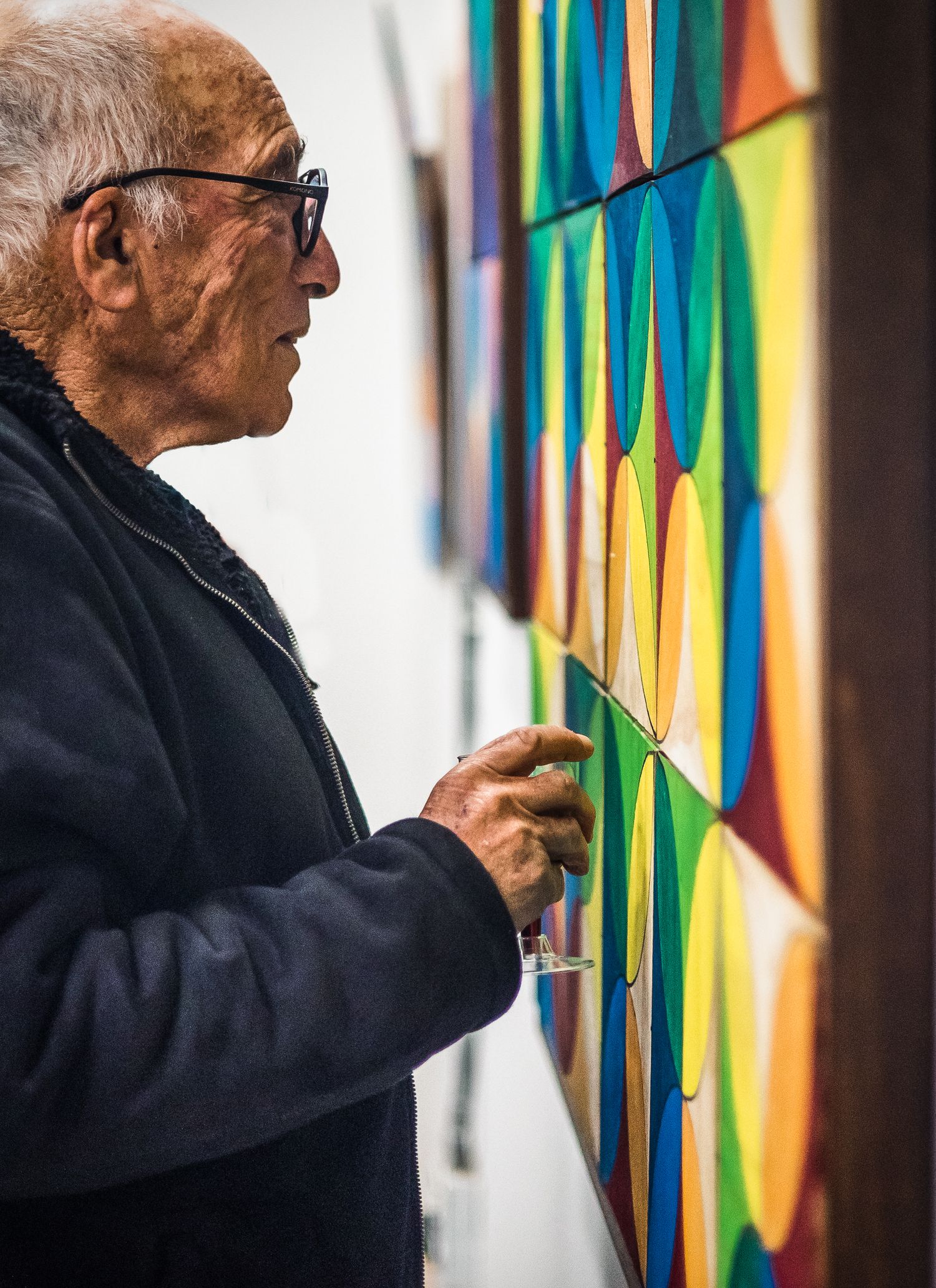Gallery visitor examining colorful geometric artwork on display.