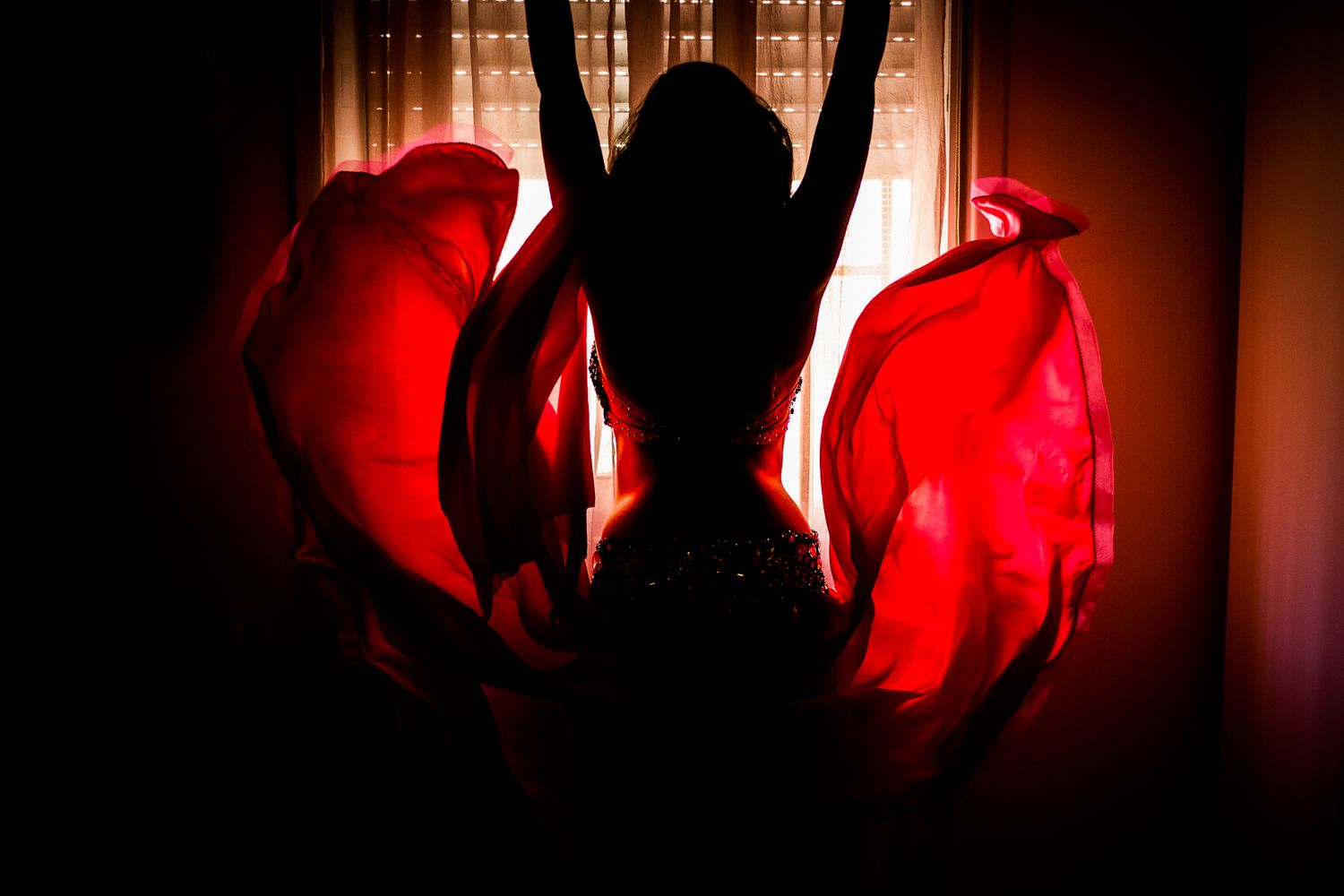 Red-lit silhouettes create mysterious atmospheric scene against warm backlight.