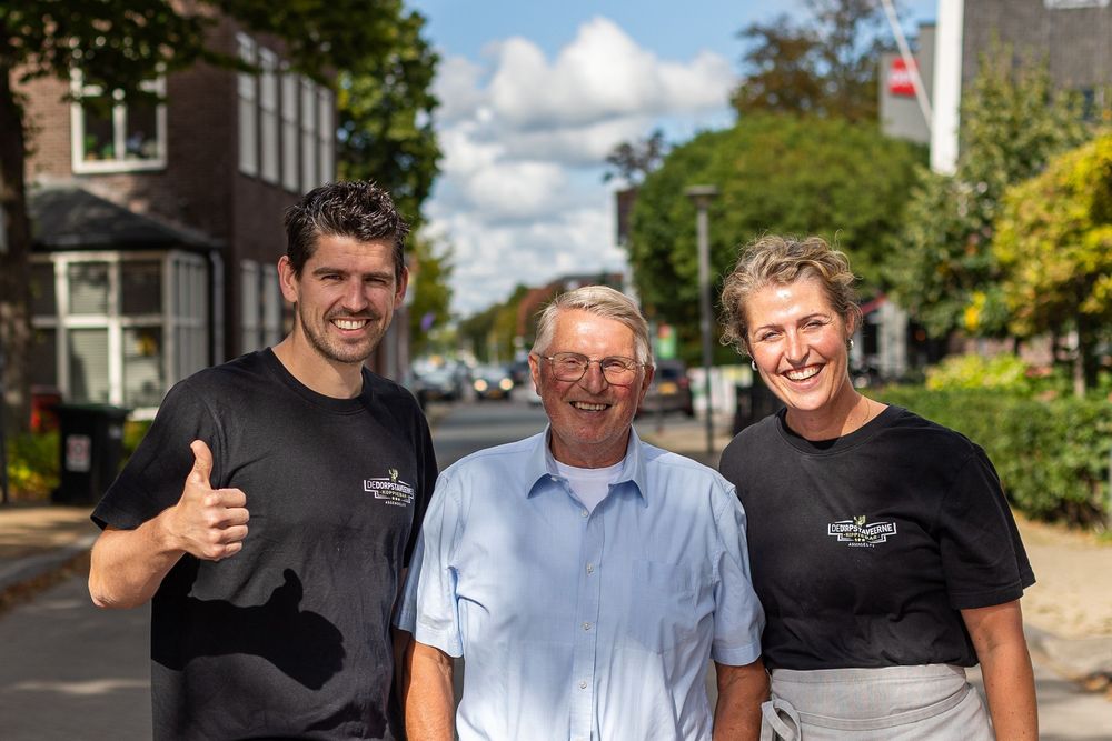Group of people standing together outdoors on a sunny day wearing black and white shirts.