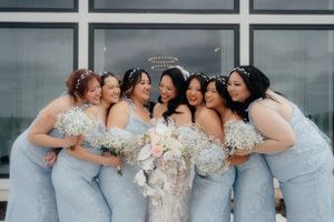 Bridesmaids in pale blue dresses huddle together for a group photo with their bouquets.