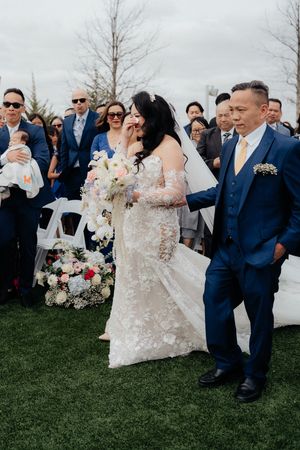 Wedding guests observe an emotional outdoor ceremony moment.