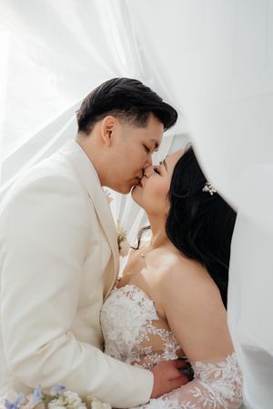 Intimate wedding portrait of couple sharing a tender moment against white backdrop.