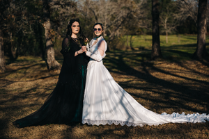 A couple in wedding attire poses together in a wooded outdoor setting during their wedding photoshoot.