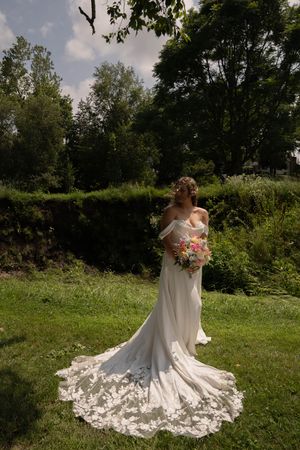 Elegant bridal portrait showing the dramatic lace train of a white wedding gown in a garden setting.