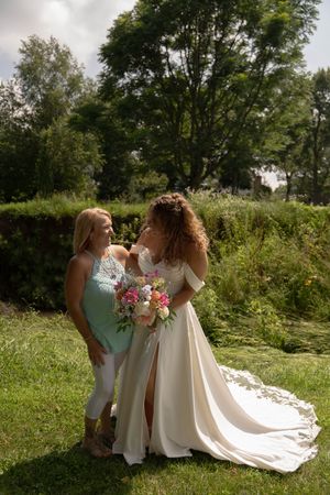 Bridesmaids in mint green dresses assist with the bride's flowing train during an outdoor photo session.