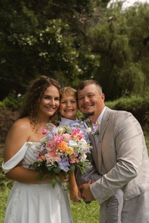 A joyful wedding party moment captured outdoors with colorful floral bouquets.