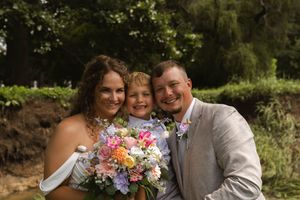 A joyful wedding party moment captured outdoors with laughter and a colorful bouquet.