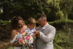 A couple shares an intimate moment during their outdoor wedding photoshoot with vibrant pink and white floral bouquet.