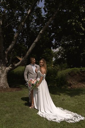 Elegant wedding portrait showing full length of bride's flowing white dress train in natural setting.