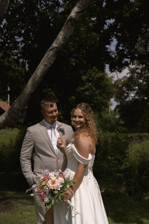 Candid wedding moment captured in outdoor garden setting with summer greenery.