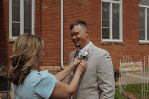 Wedding party members sharing joyful moments outside a brick building.