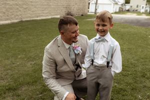 A heartwarming interaction between two wedding attendees in formal attire on a grassy lawn.