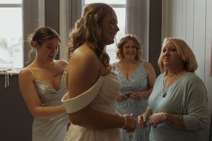 Wedding preparations taking place in a bright indoor setting with multiple attendants.