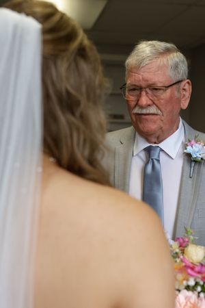 An emotional moment captured during a wedding with soft lighting and floral boutonniere details.