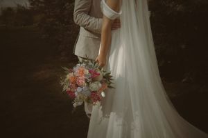 Close-up of a bride holding a pink and white floral bouquet against her white wedding gown.