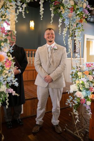 A wedding ceremony setup with a floral arch featuring colorful blooms and hanging decorations.