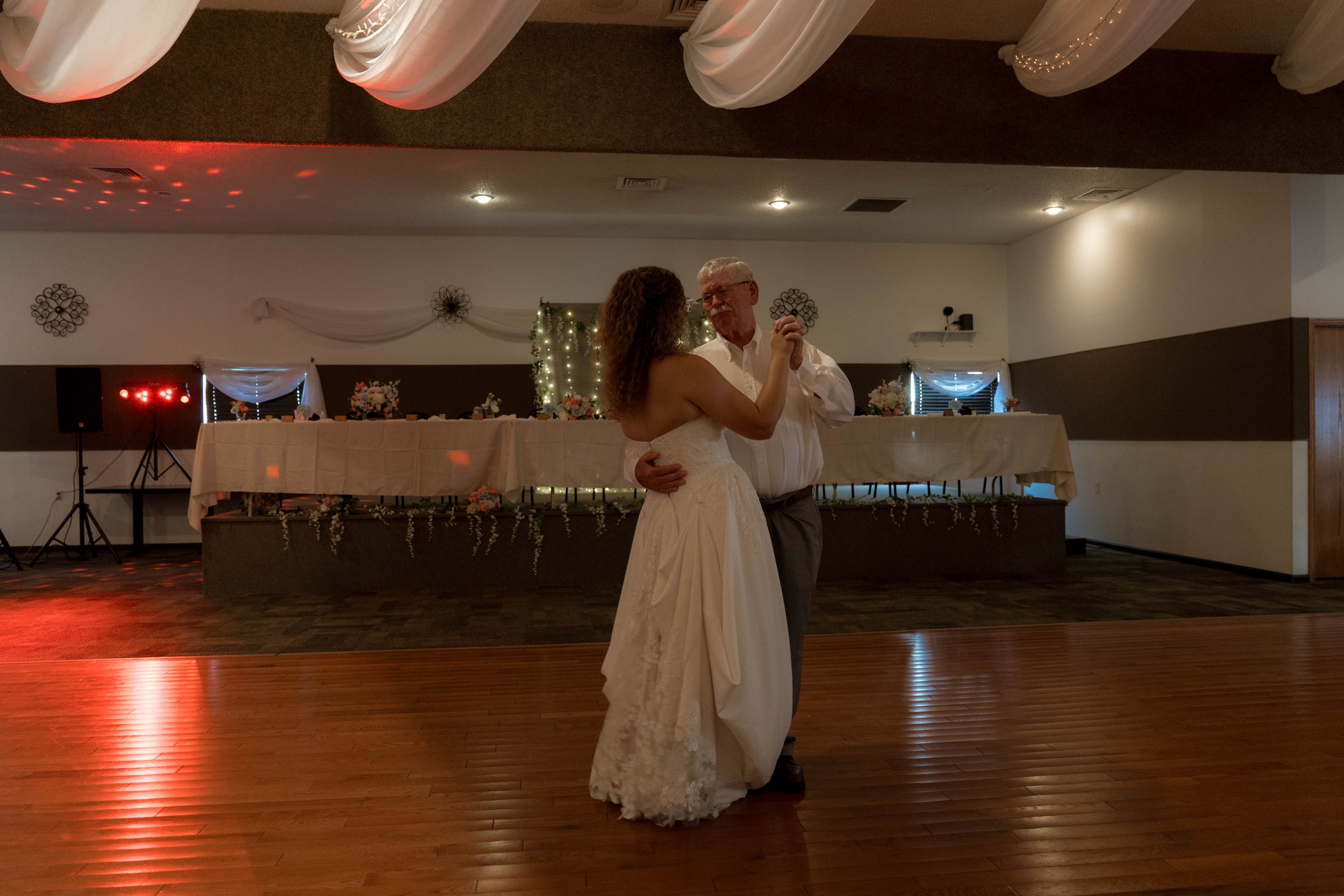 Wedding reception venue with wooden dance floor and ambient lighting.