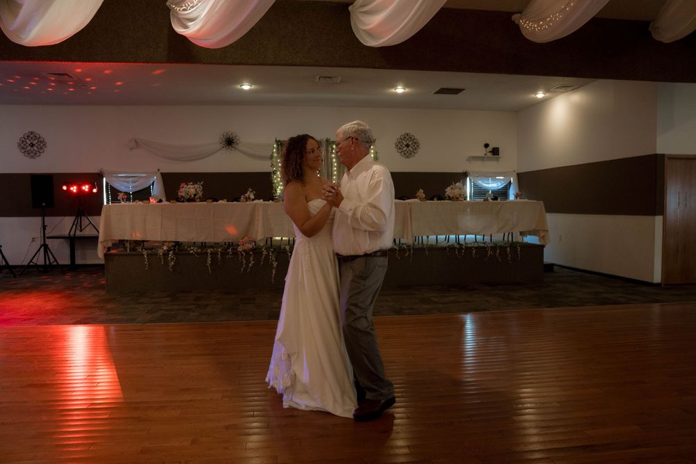 A couple shares an intimate dance on a wooden floor with dramatic red lighting in the background.