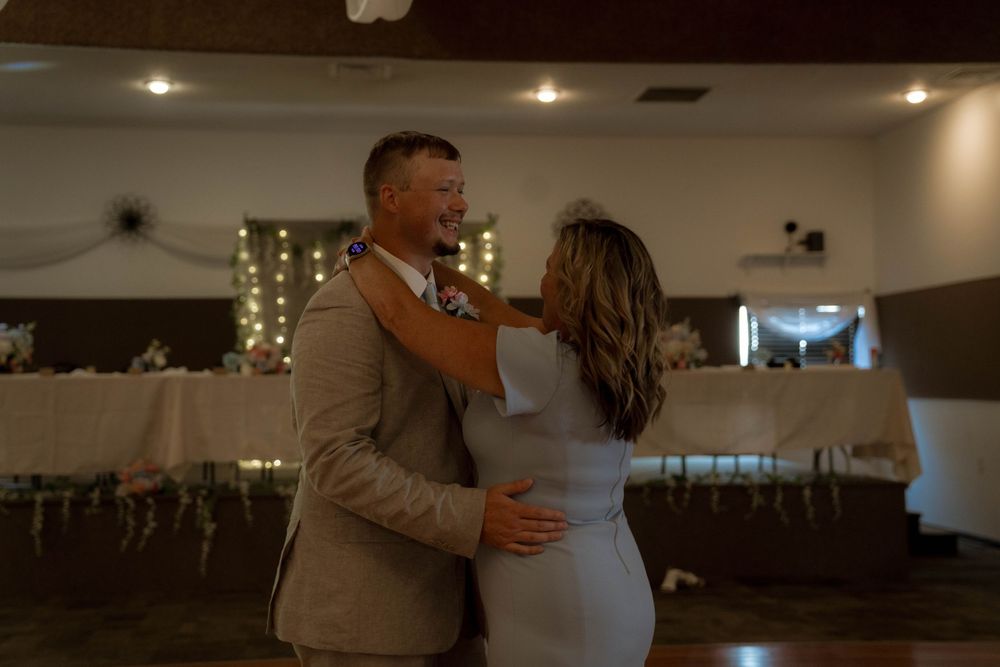 A romantic dance moment captured at a wedding reception with soft lighting and draped decor.