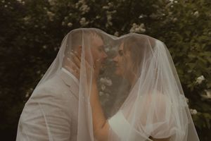 A romantic moment shared under a wedding veil in an outdoor garden setting.