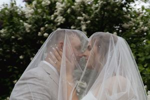 Close-up shot of bride's veil flowing in the wind against garden scenery.