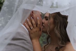 Romantic wedding portrait with flowing veil against garden backdrop.