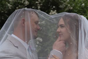Intimate wedding portrait through sheer veil with garden backdrop.