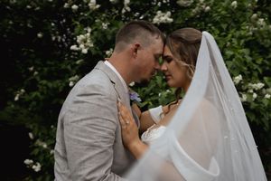 Romantic wedding portrait in garden with white flowers and grey suit details.
