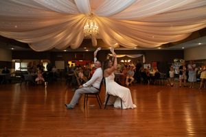 Wedding reception venue with elegant white ceiling drapes and crystal chandeliers.