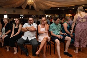 Wedding guests seated on chairs along the dance floor during reception activities.
