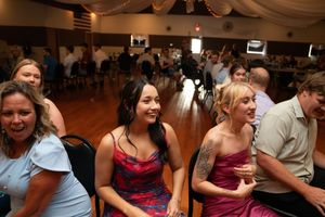 Wedding guests enjoying entertainment at reception with warm lighting and draped decor.