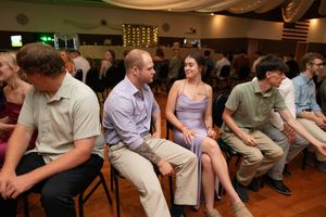 Wedding guests participating in reception games while seated in rows of chairs.