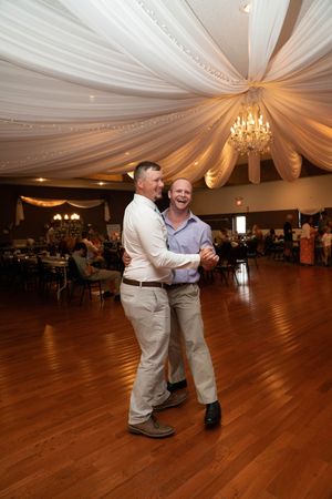Elegant ballroom with draped white fabric ceiling, crystal chandeliers, and hardwood dance floor.
