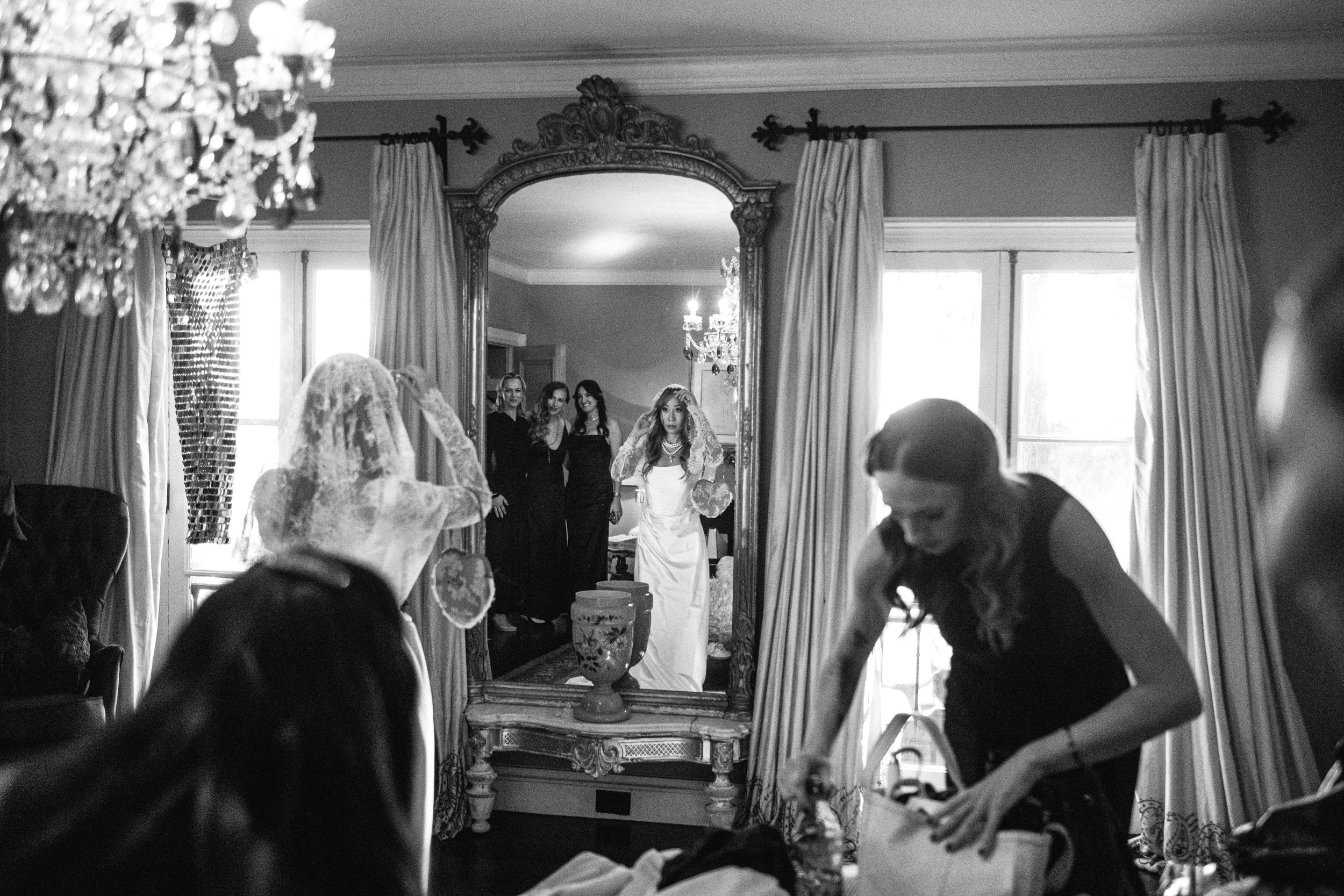 Black and white candid photo of wedding preparations in a sunlit room.